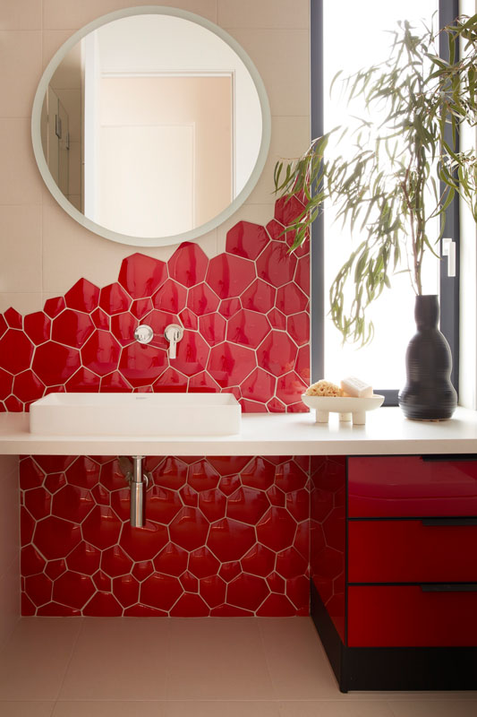 Bathroom Remodeling 63 | The Home X Custom red upholstered wall panel with modern sconces and curved mirror feature by The Home X.