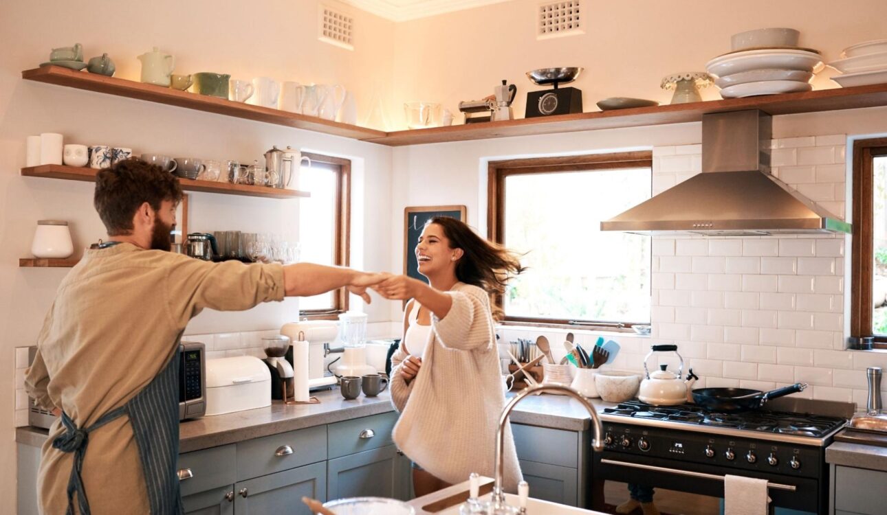 A happy young couple dances while preparing breakfast in their newly remodeled kitchen.