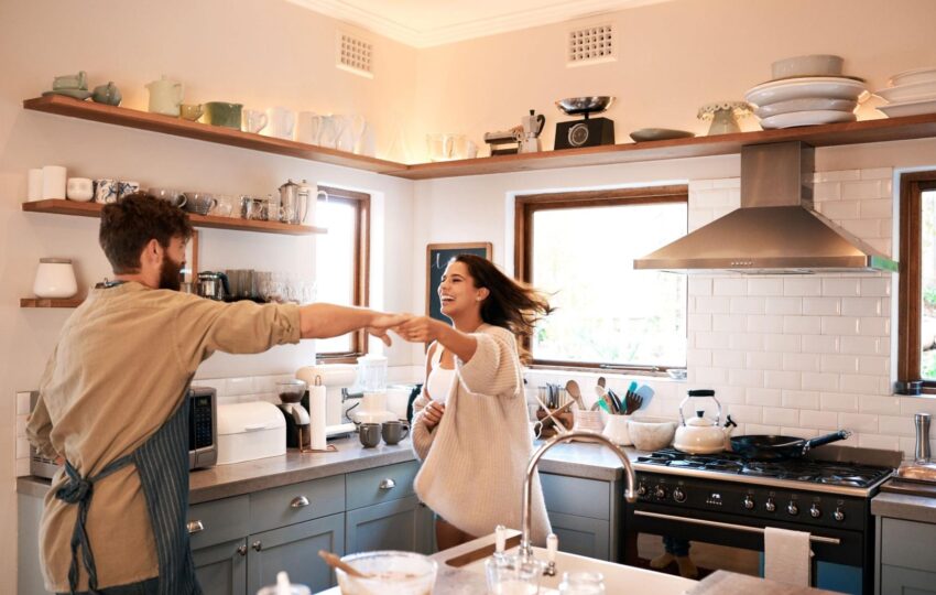 A happy young couple dances while preparing breakfast in their newly remodeled kitchen.