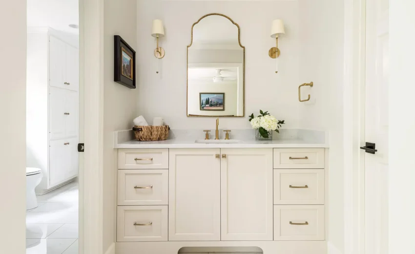 Bright white bathroom with dual vanity, arched mirrors, and brass sconces.
