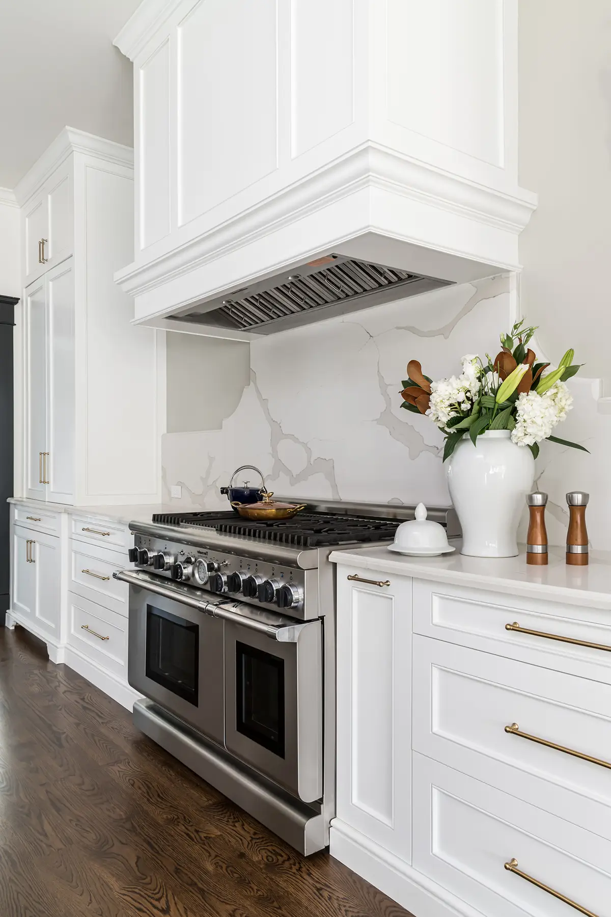 Moore St, Princeton, NJ 08540 9 | The Home X White kitchen range wall with shaker cabinets, wood flooring, and decorative hood above stainless steel oven.