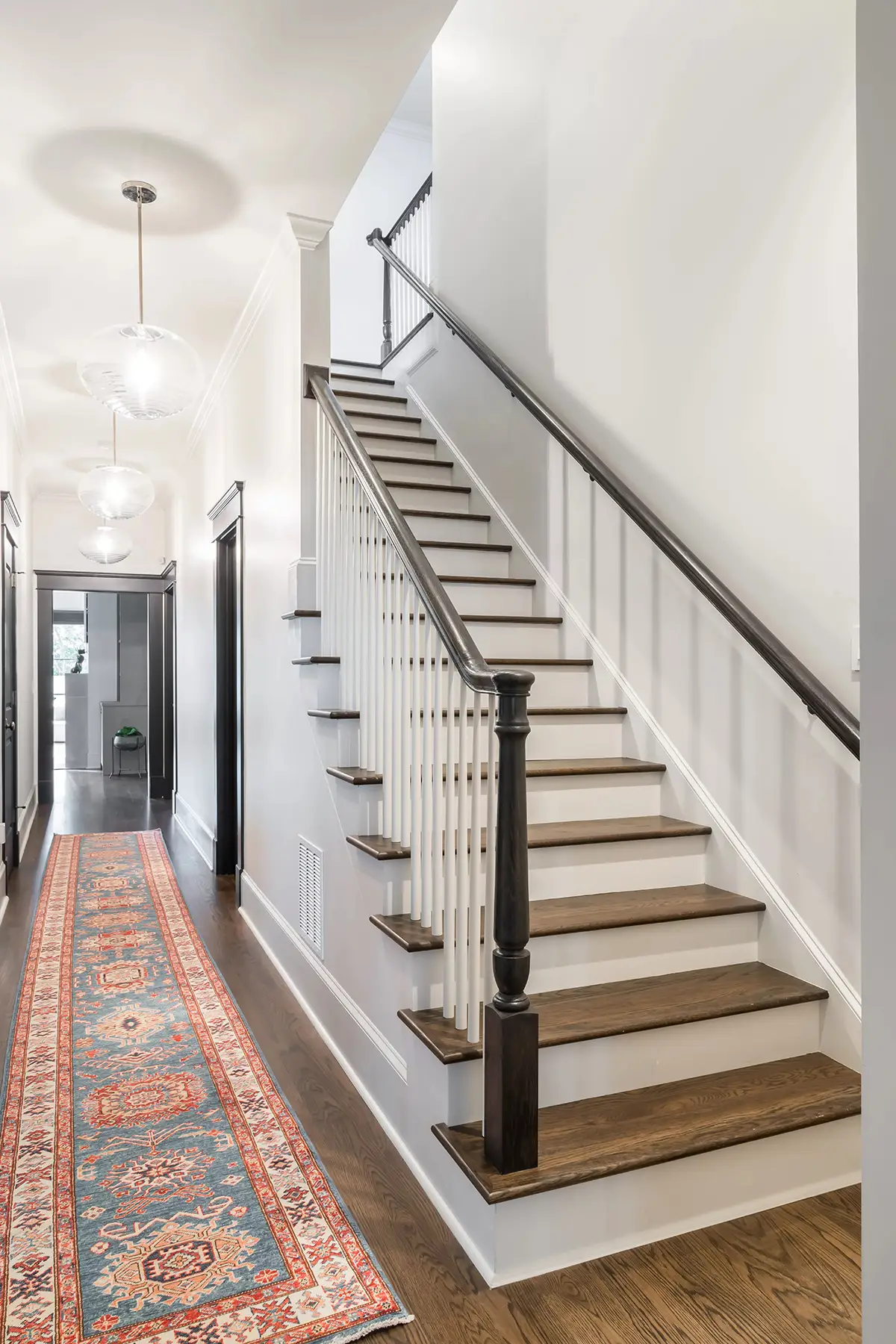 Moore St, Princeton, NJ 08540 18 | The Home X Modern staircase with black handrail, white risers, oak treads, and vintage-style hallway runner.