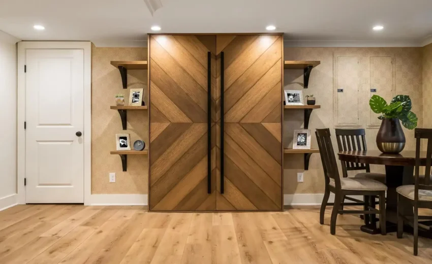 Custom chevron wood-paneled doors in a modern basement entertainment space with built-in shelving.
