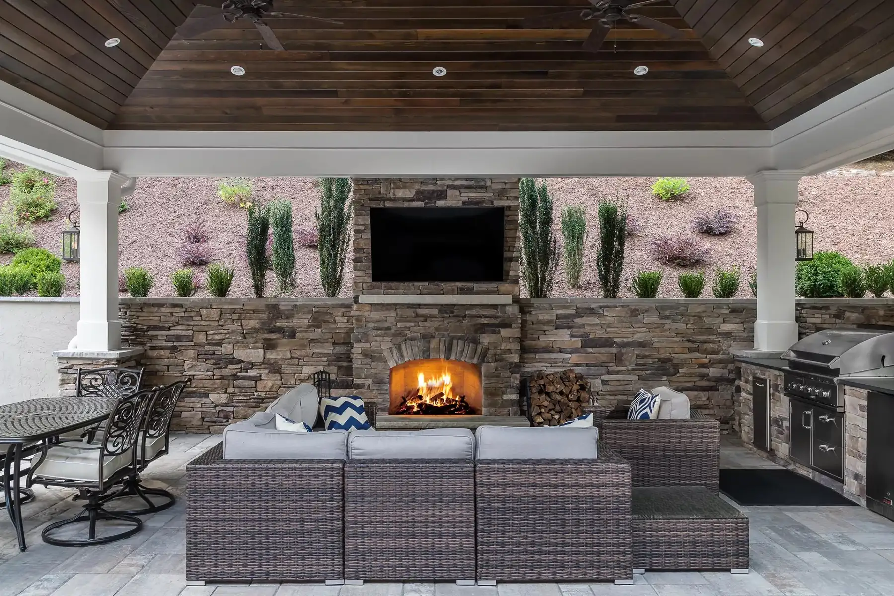 Sergeantsville Rd, Delaware Twp., 08559 1 | The Home X Covered outdoor lounge with stone fireplace, wood ceiling, and modern seating.