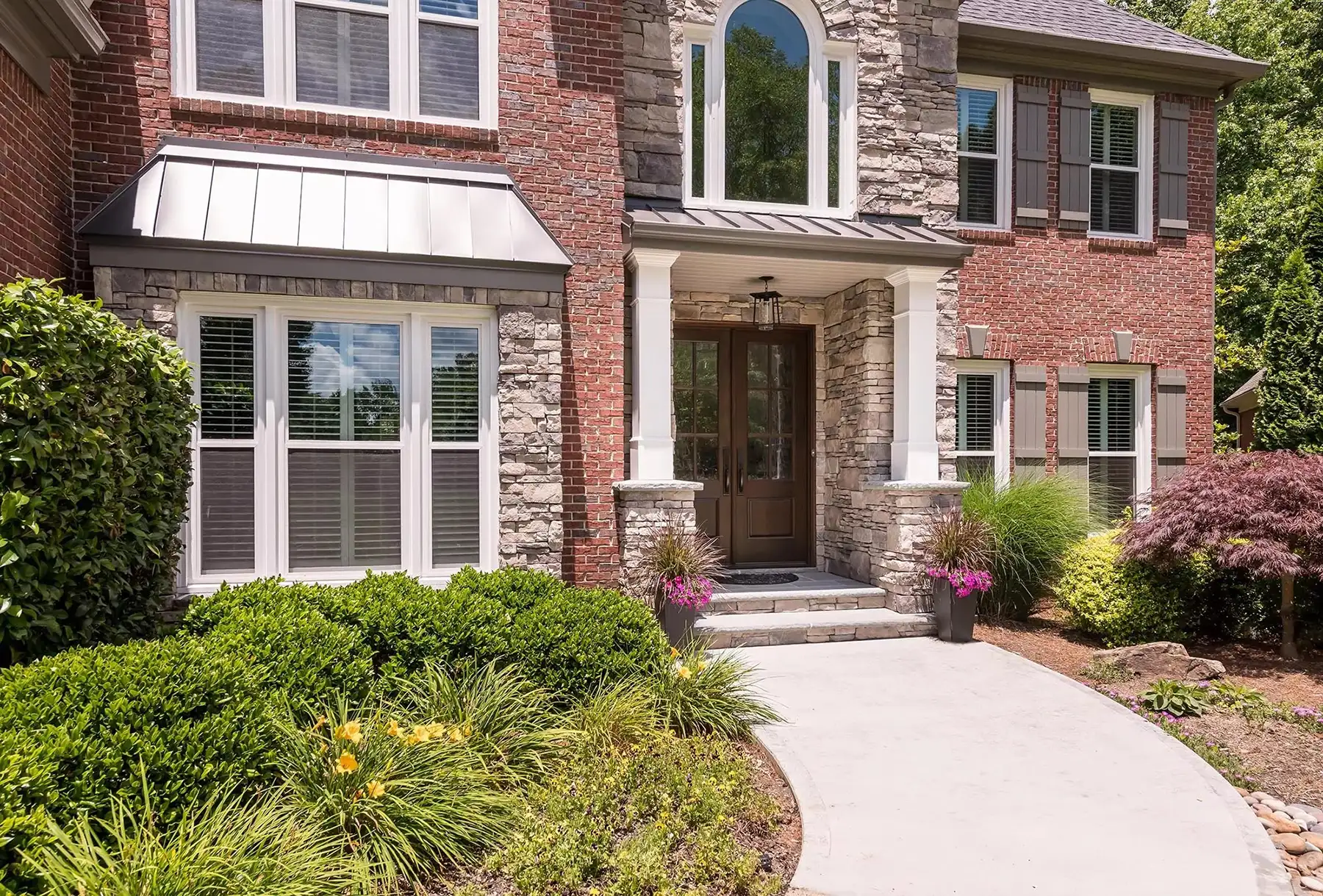 Sugan Rd, New Hope, PA 18938 1 | The Home X Elegant brick home exterior with arched entry, large windows, and a landscaped front garden path.