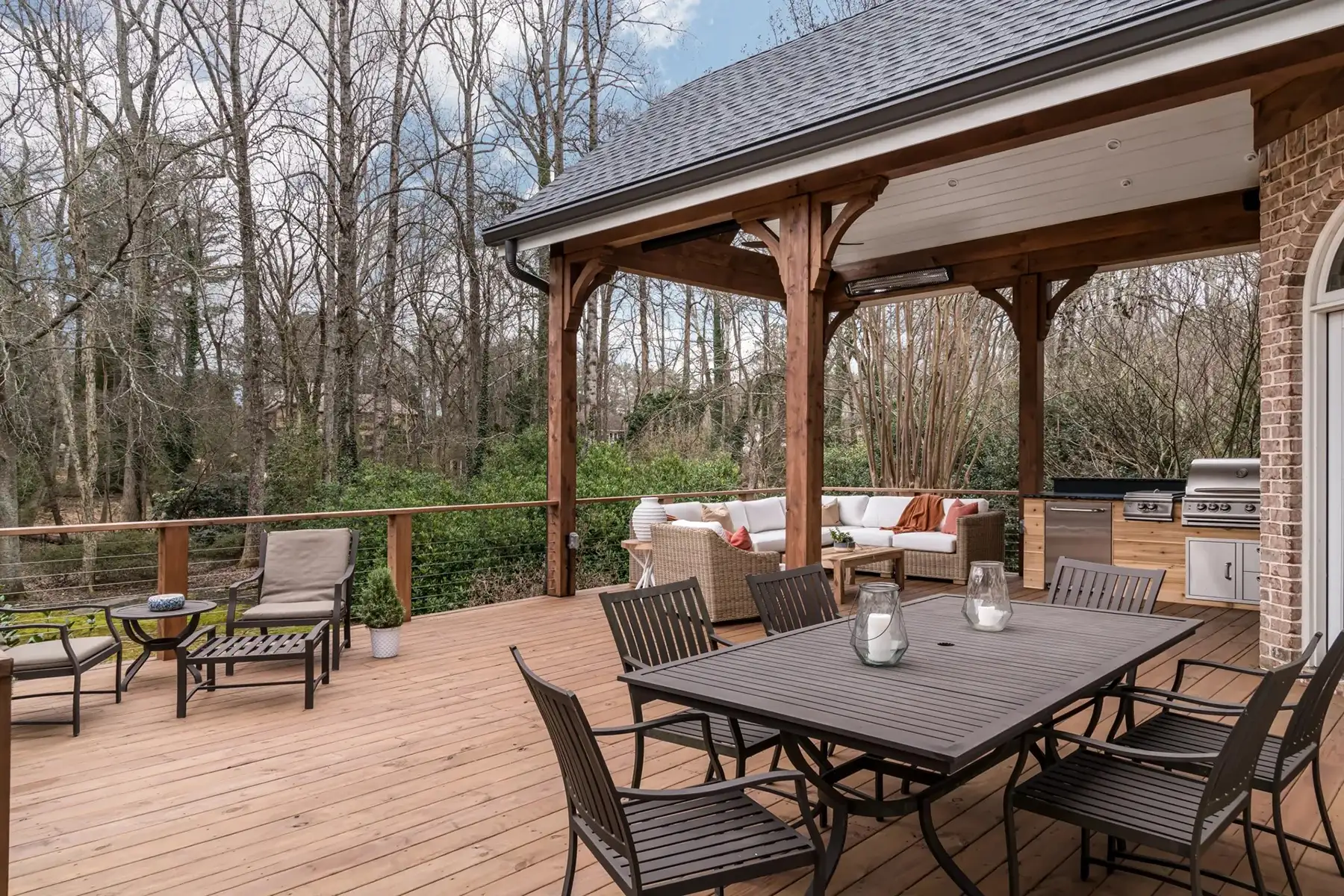 Aquetong Rd, New Hope, Pa 18938 4 | The Home X Covered patio with wood beam pergola, outdoor dining set, and stone accents surrounded by a forested backdrop.