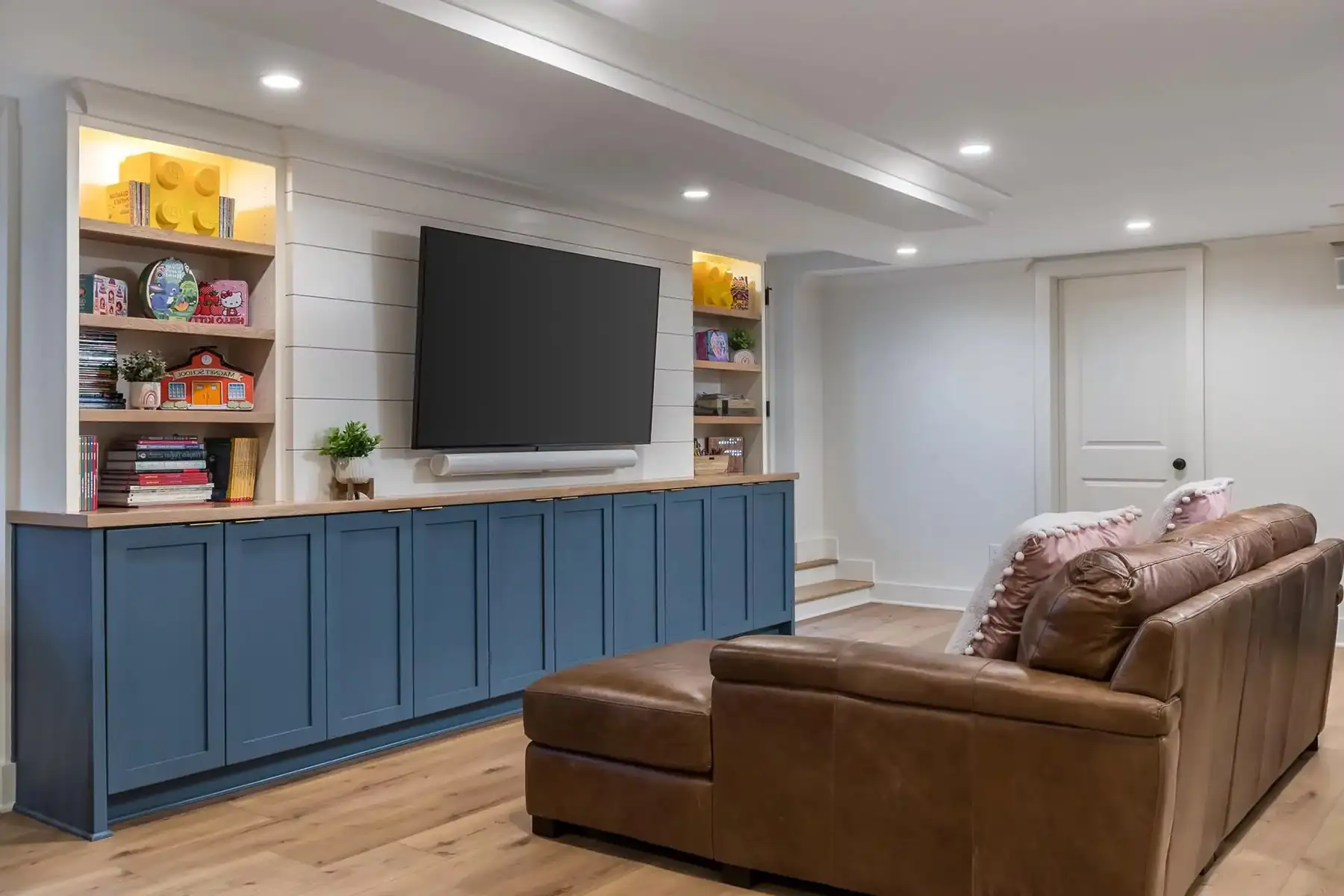 Federal City Rd, Pennington, NJ 08534 5 | The Home X Modern basement with sleek blue cabinetry, open shelving, and built-in media center.