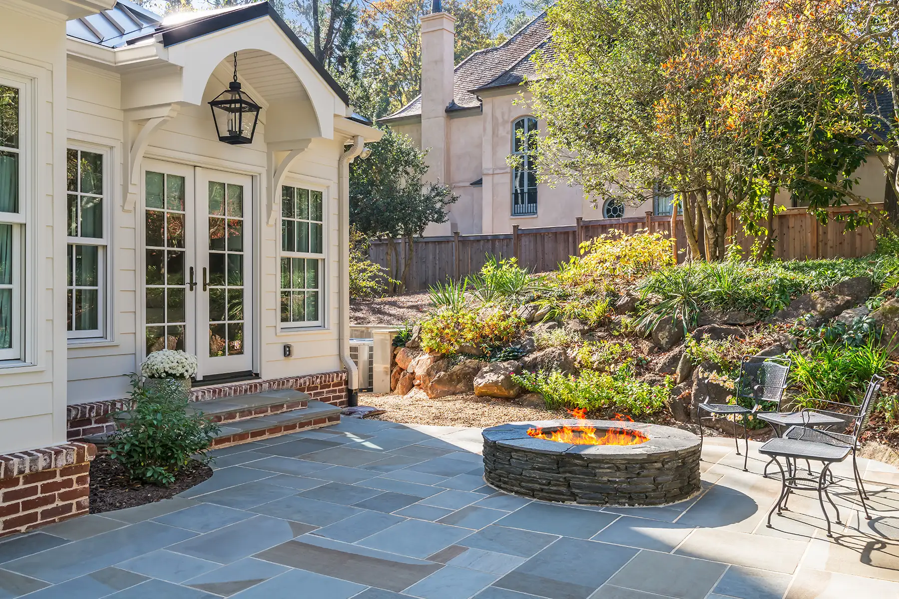 Woodside Rd, Yardley, PA 19067 3 | The Home X Backyard view of elegant sunroom addition with tiered landscaping, stone retaining walls, and curved paver patio.