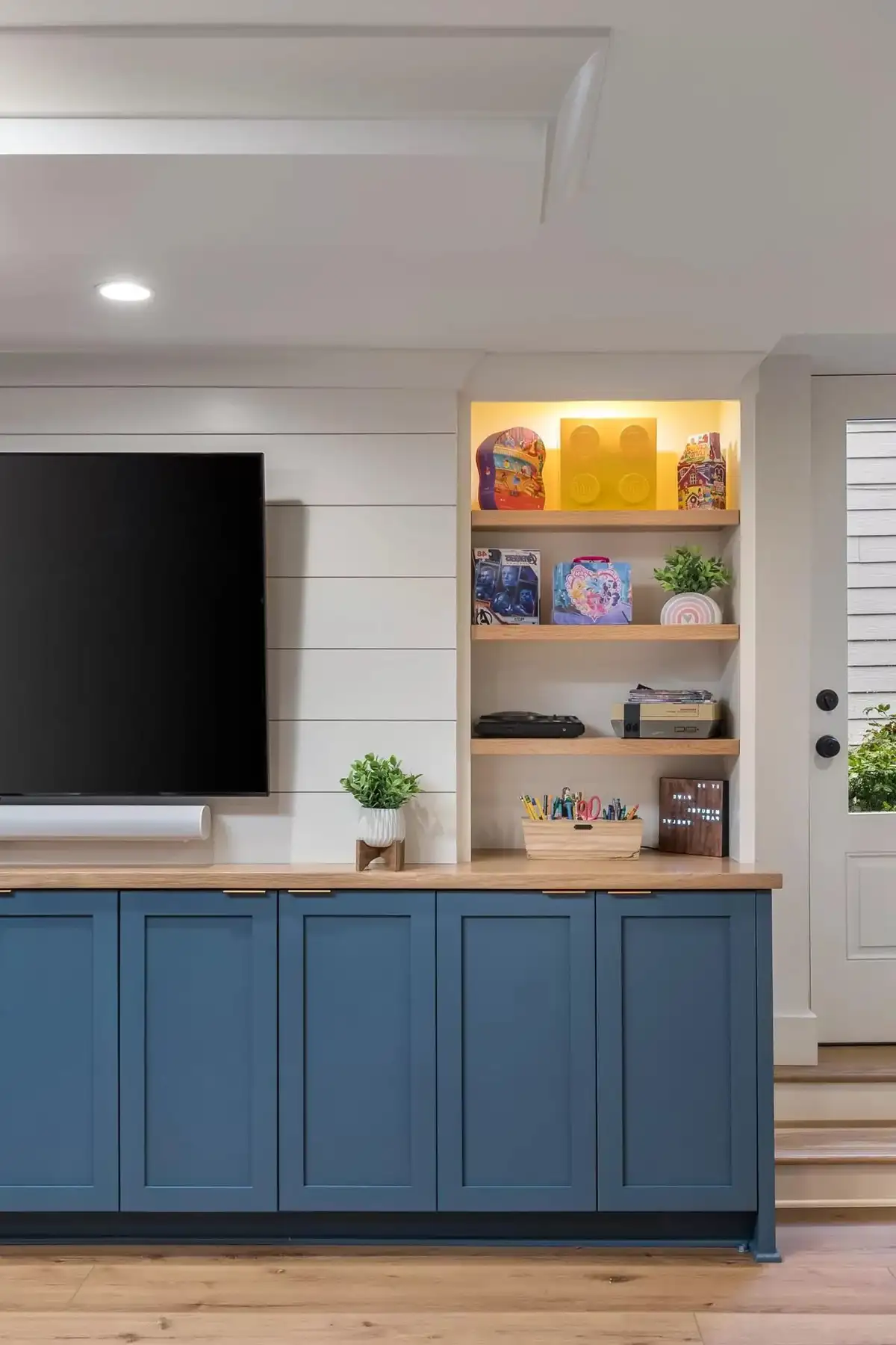 Federal City Rd, Pennington, NJ 08534 6 | The Home X Close-up of basement media wall with blue cabinetry, open shelving, and mounted TV.