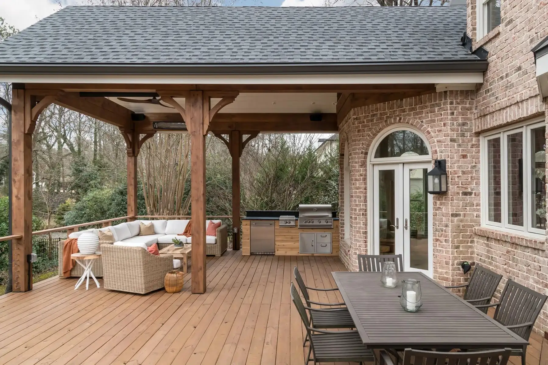 Aquetong Rd, New Hope, Pa 18938 5 | The Home X Outdoor entertaining space with composite deck, built-in grilling station, stone columns, and wood pergola attached to a brick exterior home.