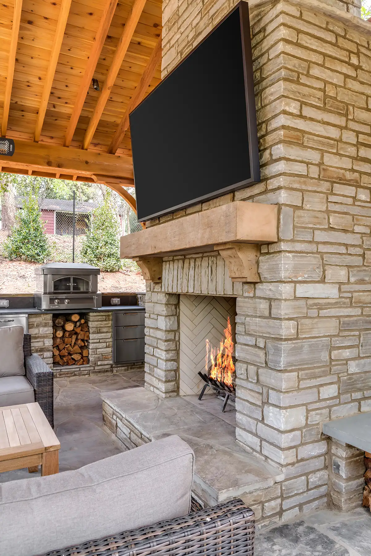 Lower Mountain Rd, New Hope, PA 18938 6 | The Home X Stone fireplace under vaulted wood ceiling in an outdoor patio with mounted TV and lounge seating in New Hope, PA.