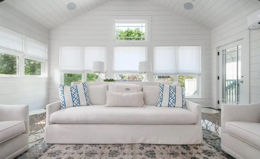 Elegant white living room with coffered ceiling, wood beams, and large windows.
