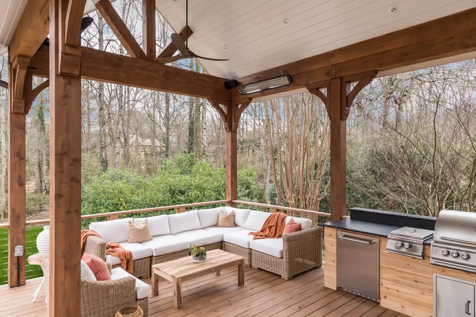Aquetong Rd, New Hope, Pa 18938 8 | The Home X Covered outdoor lounge with exposed wood beams, ceiling fan, and sectional seating overlooking a wooded backyard.