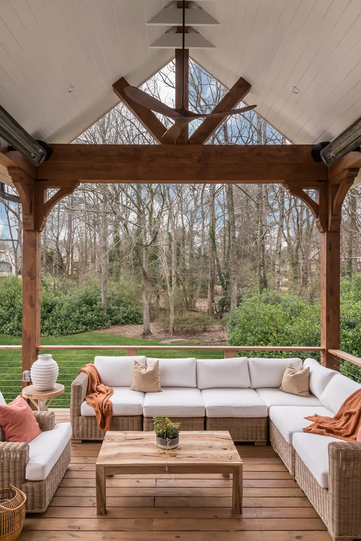 Aquetong Rd, New Hope, Pa 18938 9 | The Home X Rustic covered outdoor seating area with vaulted wood ceiling, exposed beams, and cozy lounge furniture facing a wooded backdrop.