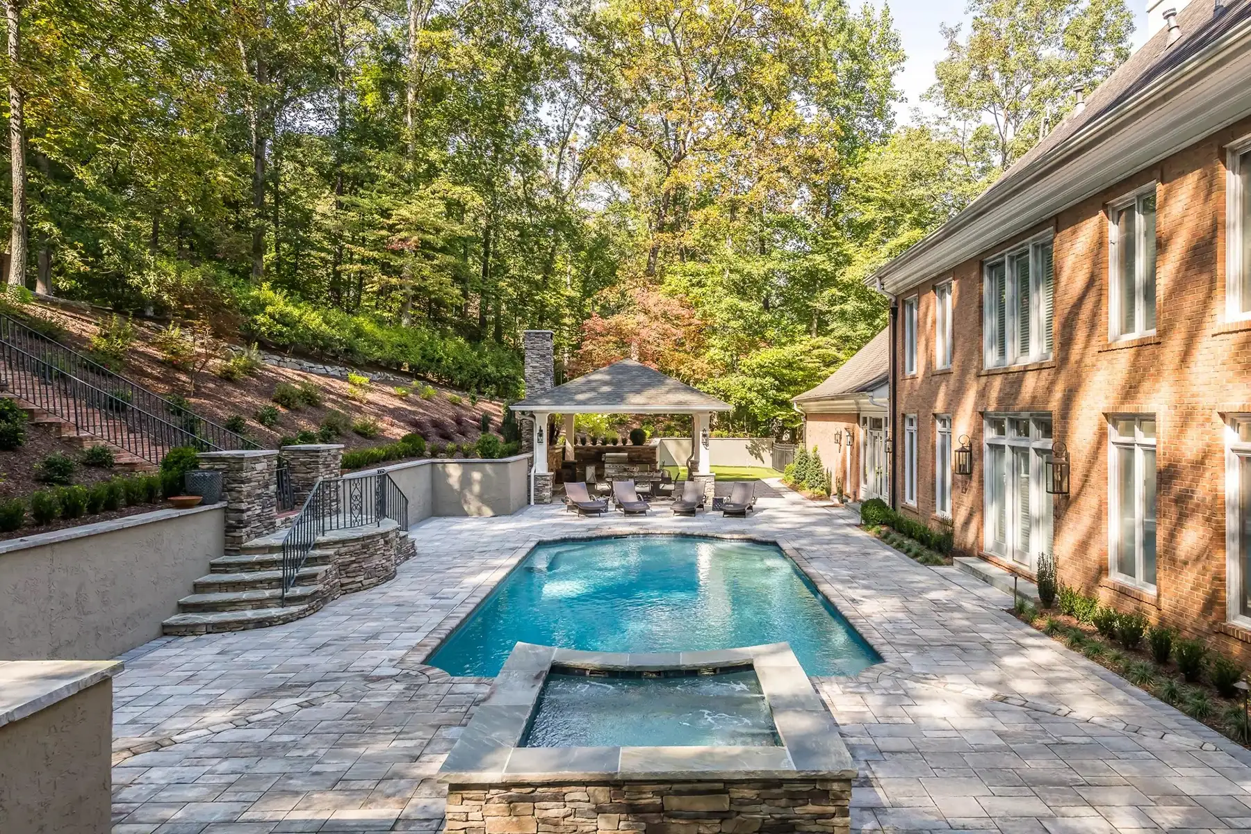 Sergeantsville Rd, Delaware Twp., 08559 8 | The Home X Elegant rectangular pool with integrated spa and seating area surrounded by stone patio and warm-toned brick home.