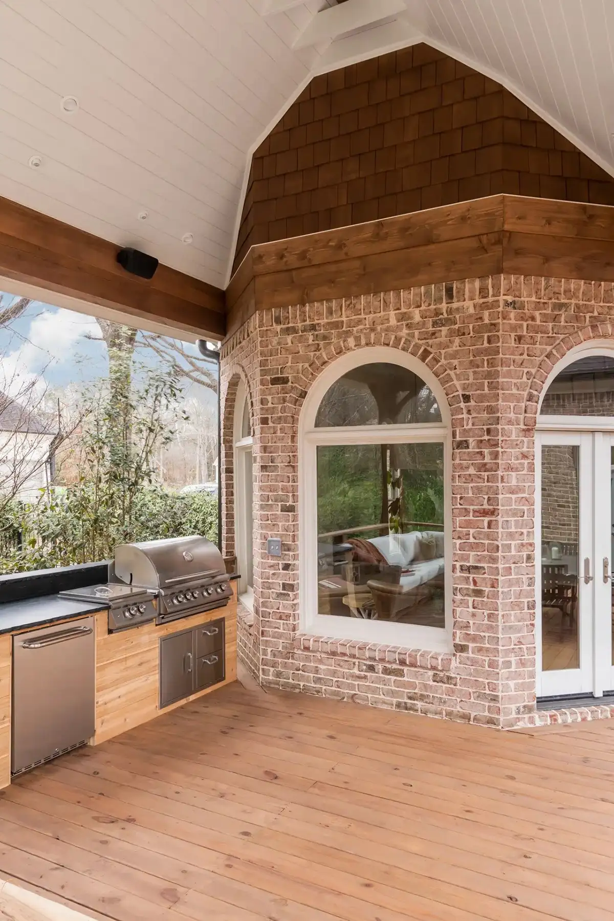 Aquetong Rd, New Hope, Pa 18938 10 | The Home X Arched brick entryway with glass doors leading to a covered outdoor space featuring a warm-toned tile floor and rustic wood ceiling.