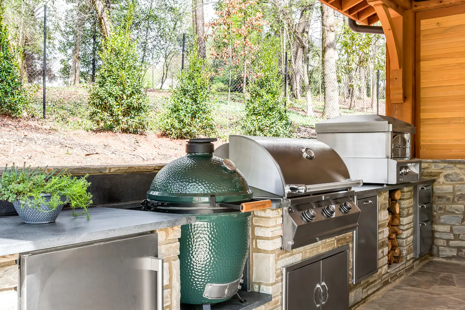 Lower Mountain Rd, New Hope, PA 18938 7 | The Home X Covered outdoor dining area with wood beam ceiling, stone fireplace, and green cabinets in New Hope, PA.