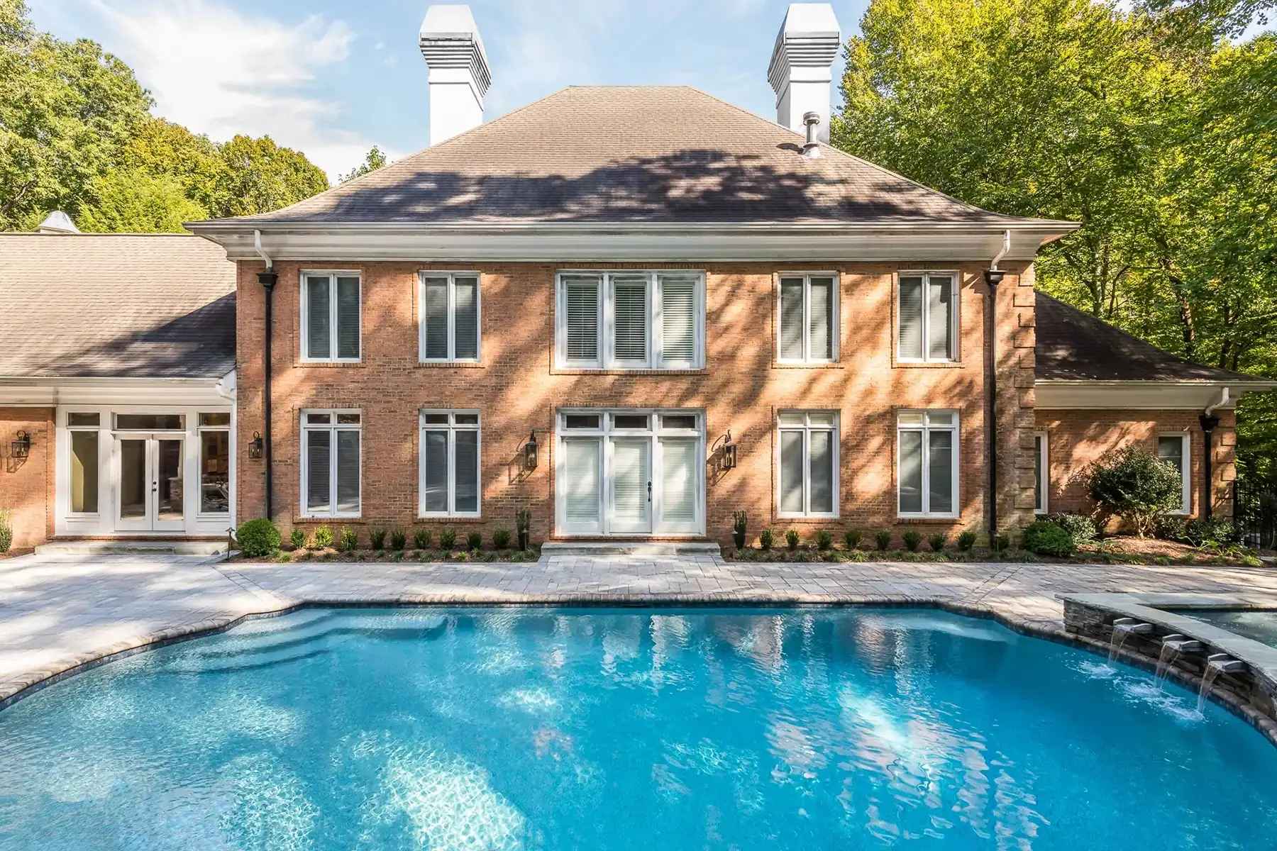 Sergeantsville Rd, Delaware Twp., 08559 9 | The Home X Luxury pool with sun deck and steps, positioned in front of a grand brick home with arched windows and upper balcony.
