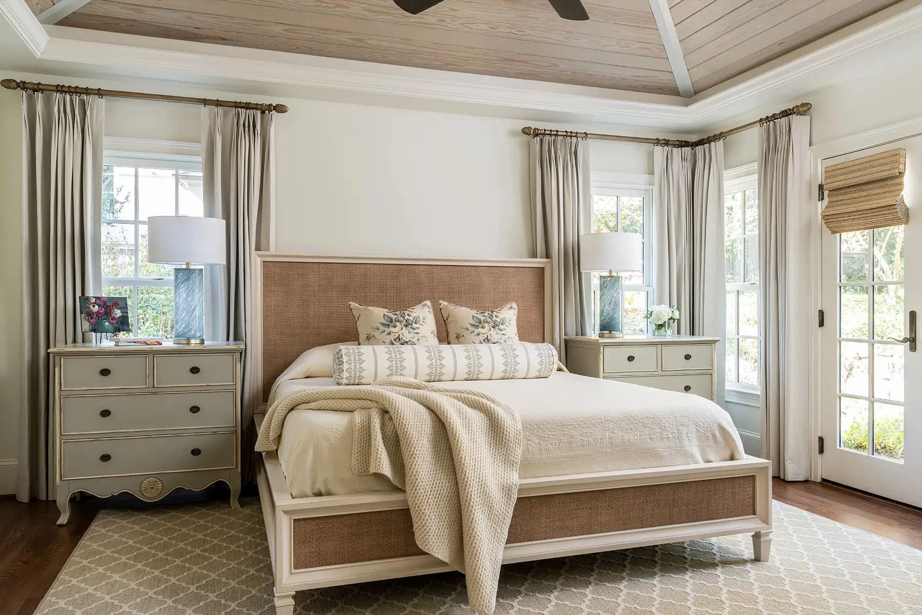 Woodside Rd, Yardley, PA 19067 8 | The Home X Elegant primary bedroom with beige upholstered bed, twin nightstands, and surrounding windows with drapery.