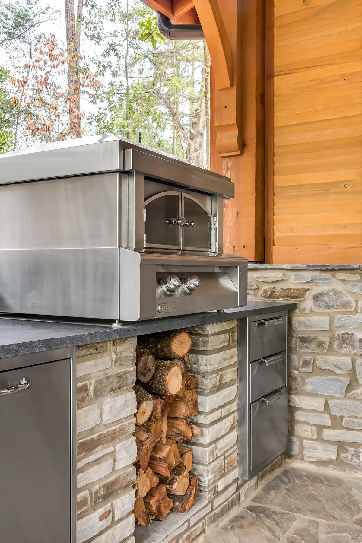 Lower Mountain Rd, New Hope, PA 18938 8 | The Home X Outdoor kitchen with built-in stainless grill, stone facade, and wood beam ceiling in New Hope, PA.