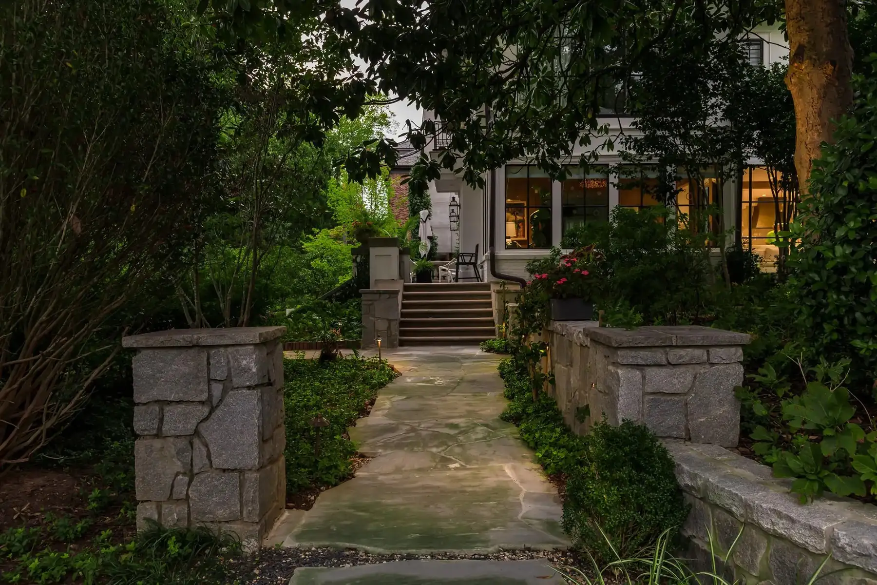 Pidcock Creek Rd, New Hope, PA 18938 11 | The Home X Twilight view of a stone garden entry with lush greenery and pathway lighting in New Hope, PA.