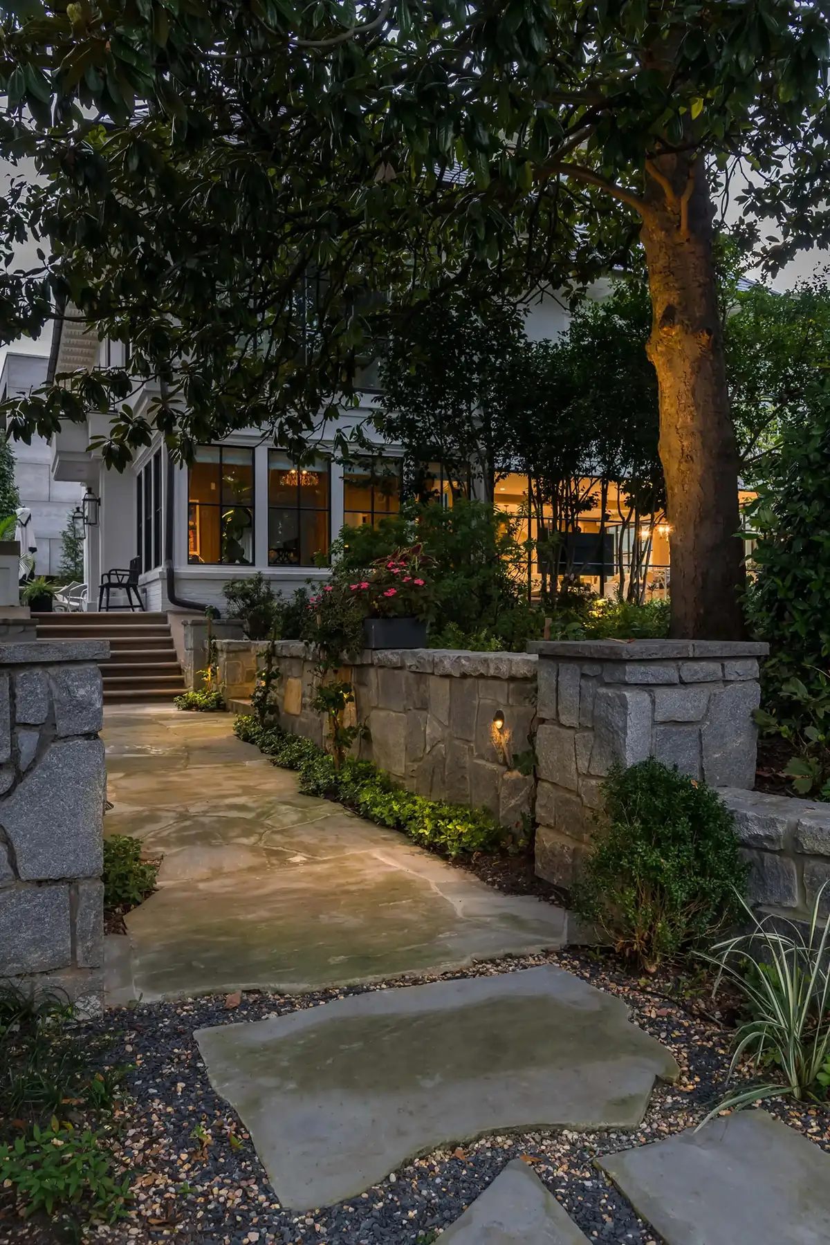 Pidcock Creek Rd, New Hope, PA 18938 12 | The Home X Twilight scene of a landscaped garden path with stone steps and warm uplighting at a New Hope, PA home.