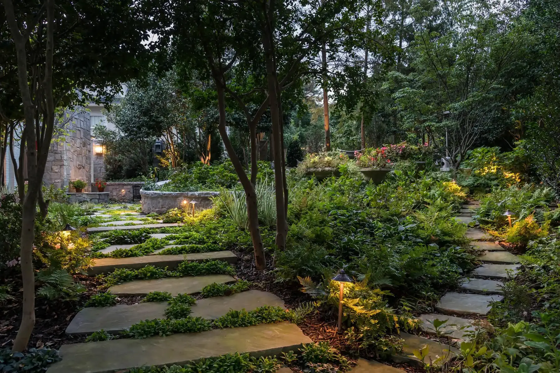 Pidcock Creek Rd, New Hope, PA 18938 13 | The Home X Twilight view of a lush garden with stone pavers, ambient lighting, and layered plantings in New Hope, PA.