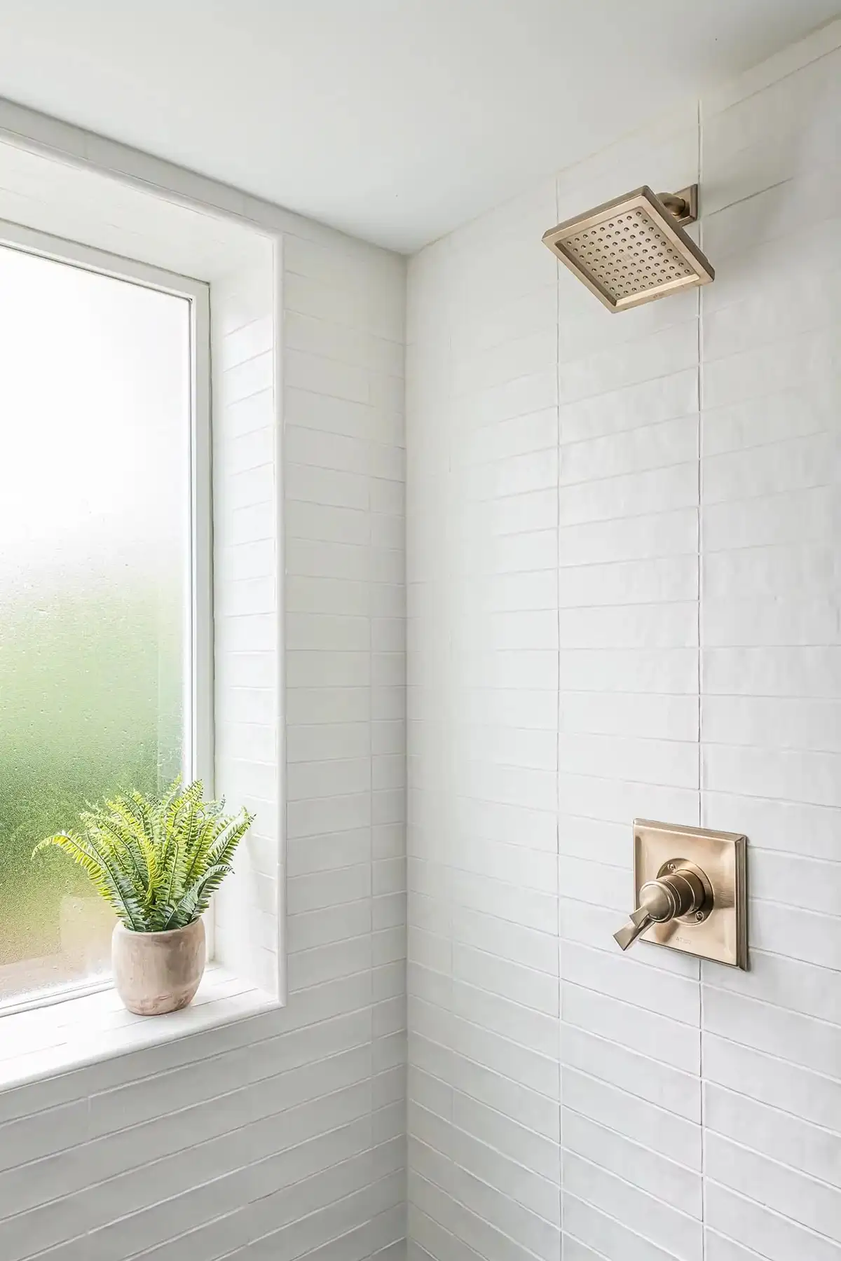 Federal City Rd, Pennington, NJ 08534 1 | The Home X Minimalist shower with vertical white tile, brass fixtures, and a frosted window.