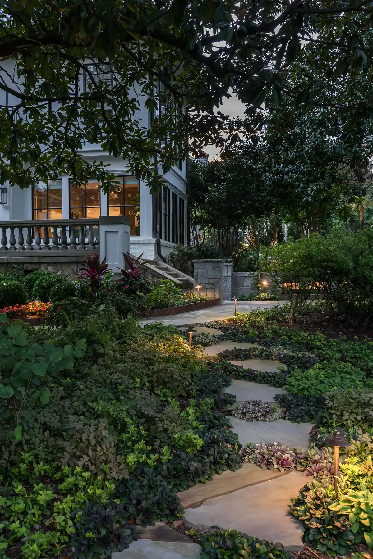 Pidcock Creek Rd, New Hope, PA 18938 14 | The Home X Evening garden with a winding stone path, soft landscape lighting, and cottage-style home in the background.