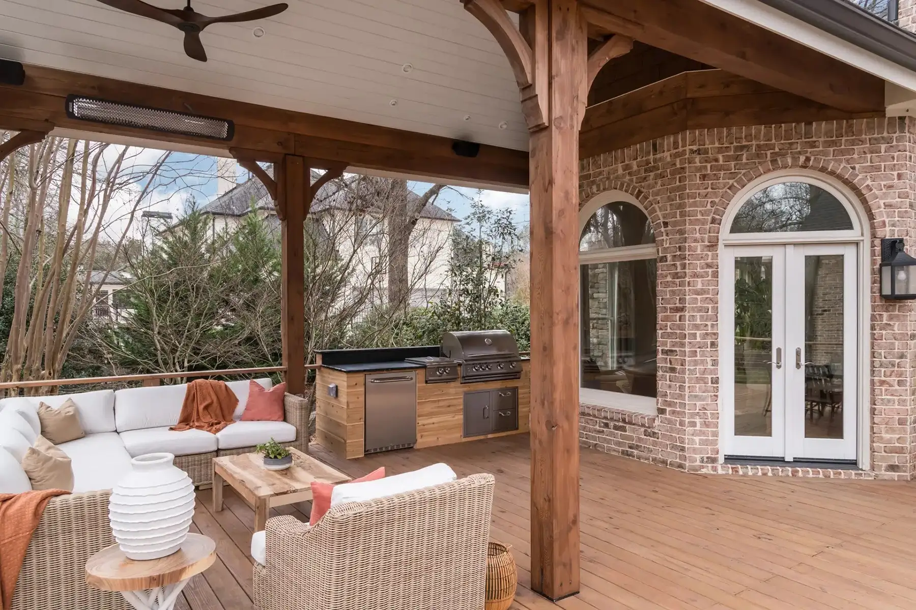 Aquetong Rd, New Hope, Pa 18938 11 | The Home X Outdoor living area featuring brick walls, French doors with arched transoms, and exposed wood beams over a natural wood deck.