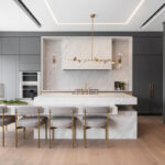 Minimalist luxury kitchen remodel with waterfall island, brass fixtures, and flat-panel cabinetry by The Home X.