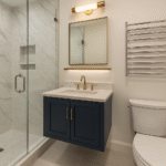 Modern small bathroom remodel with navy floating vanity, marble top, glass shower, and brass fixtures