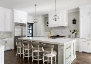 Elegant white kitchen with marble backsplash, large island, and pendant lighting.