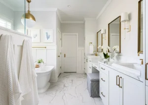 Bright white bathroom featuring double vanity with quartz countertops, large framed mirror, and a walk-in shower with glass enclosure.