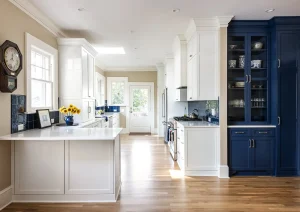 Open-concept kitchen with white cabinetry, wood flooring, and a bold navy-blue built-in pantry wall.