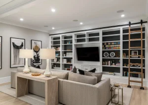 Elegant basement living room with custom built-ins, recessed lighting, and neutral furniture in Newtown PA remodel