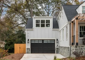 Modern farmhouse exterior with white vertical siding, black-framed windows, and attached garage.