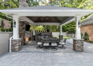 Covered outdoor dining area with wood ceiling, stone columns, and modern table setting.