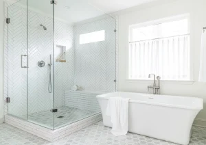 White spa-like bathroom with freestanding tub, large glass shower, and vertical window shade.