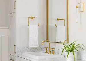 Luxury walk-in shower with marble-look tile, built-in niche, glass enclosure, and brushed gold fixtures.