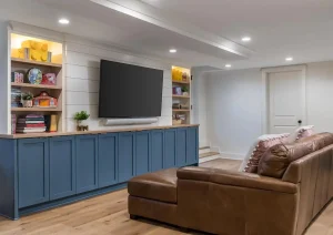 Modern basement with sleek blue cabinetry, open shelving, and built-in media center.