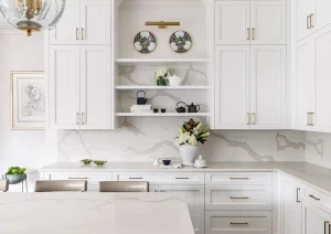 Bright white kitchen with integrated range hood, floating wood shelves, and marble backsplash.