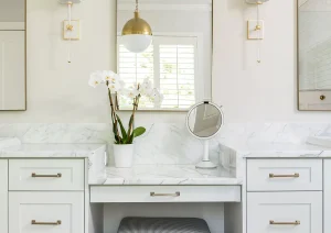 Double vanity bathroom with modern gray cabinets, white quartz countertop, and brass sconces.