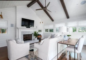 Modern white dining area with vaulted ceilings, exposed beams, and black-framed windows.