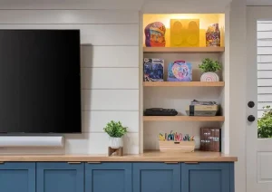 Close-up of basement media wall with blue cabinetry, open shelving, and mounted TV.