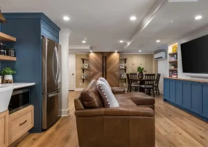 Wide-angle view of finished basement with built-in media wall, seating area, and natural wood flooring.
