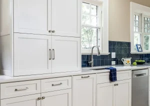 Bright white transitional kitchen with shaker cabinets, blue tile backsplash, and stainless steel appliances.