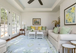 Bright sunroom interior with vaulted ceiling, soft neutral furnishings, and surrounding windows for natural light.