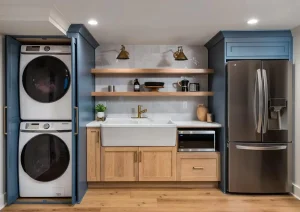 Modern laundry nook with stacked washer and dryer, floating wood shelves, and built-in blue cabinets.
