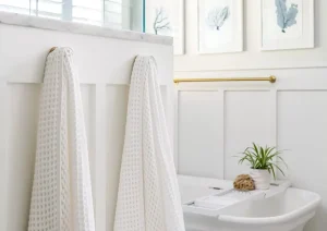 Elegant bathroom with freestanding tub, brushed gold fixtures, and white curtain accents.